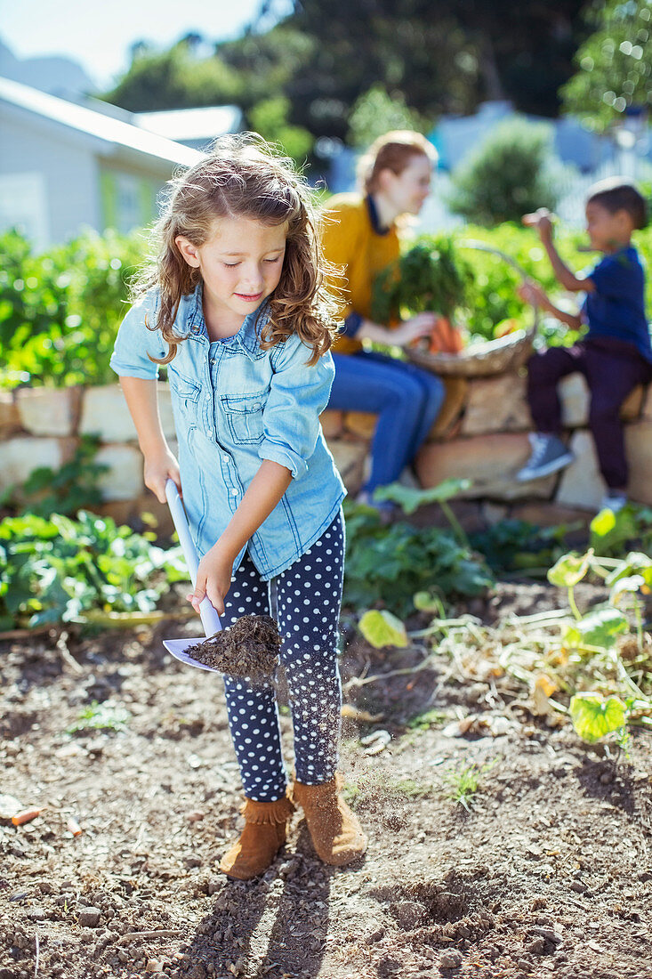 Girl shovelling dirt in garden