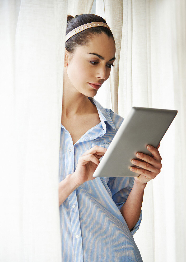 Woman using digital tablet at window