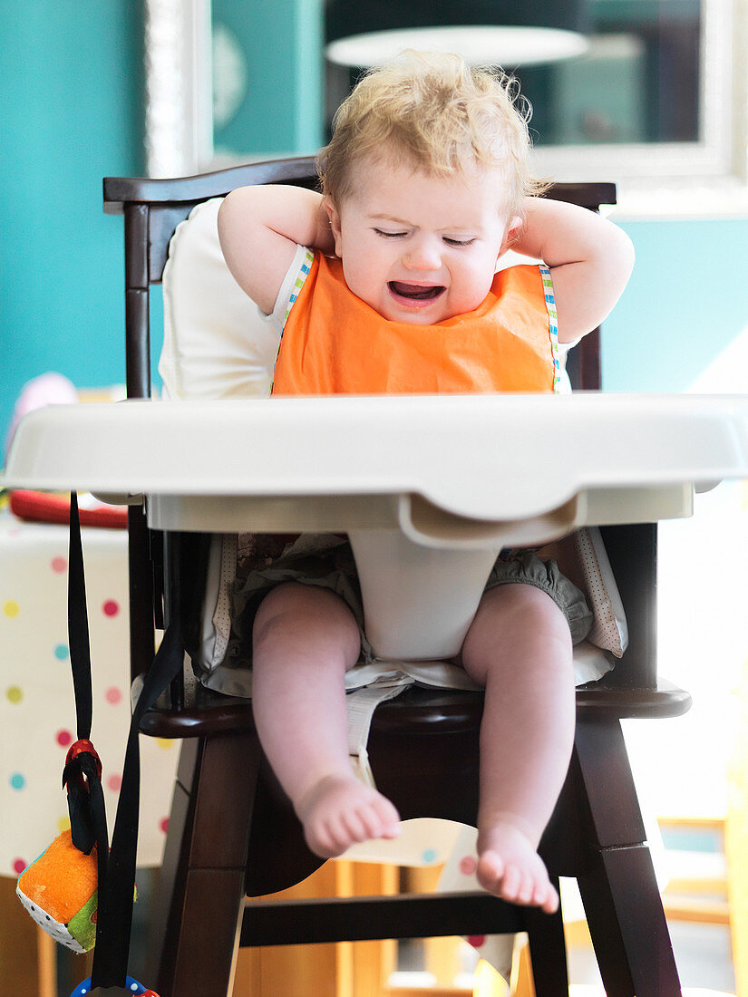 Baby girl crying in high chair