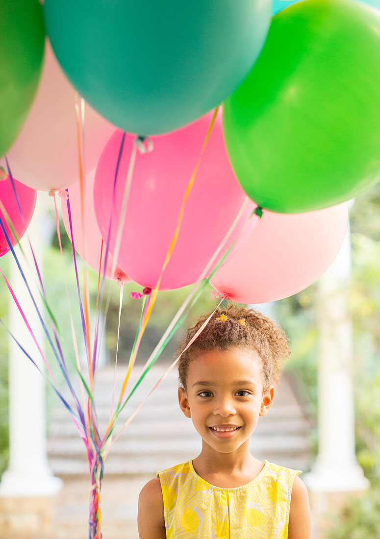 Young girl holding bunch of balloons
