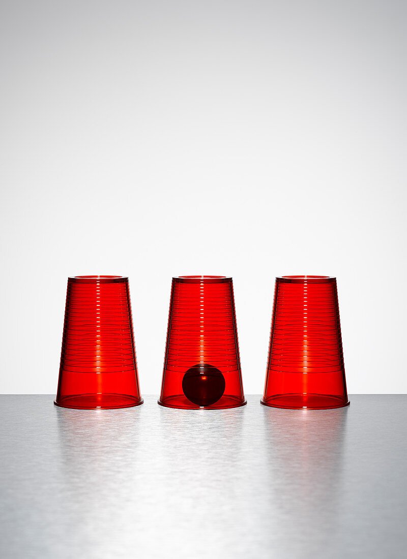 Ball under middle of three clear red cups