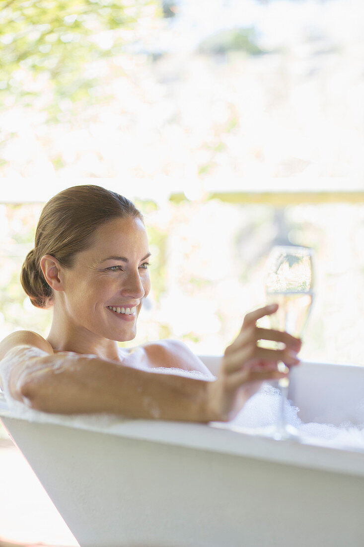 Woman drinking champagne in bathtub
