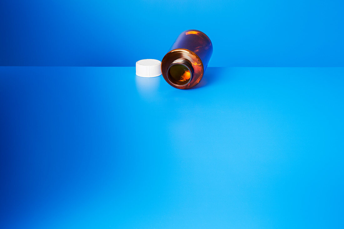 Empty pill bottle open on blue counter