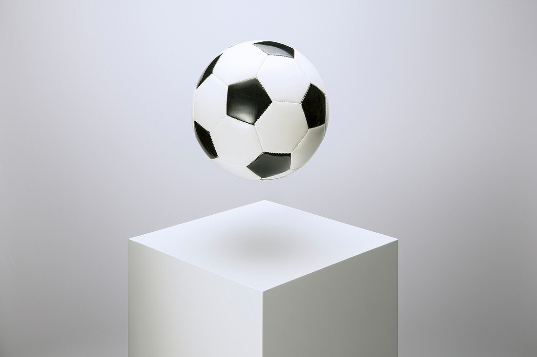 Soccer ball hovering over pedestal