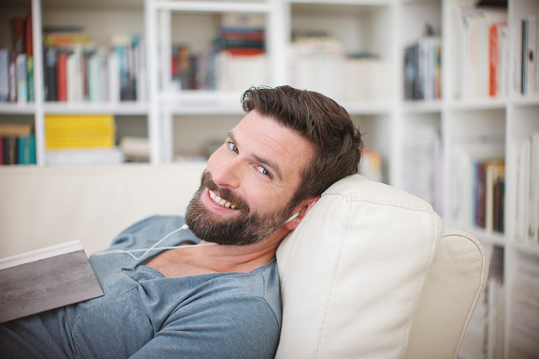 Smiling man listening to music on sofa