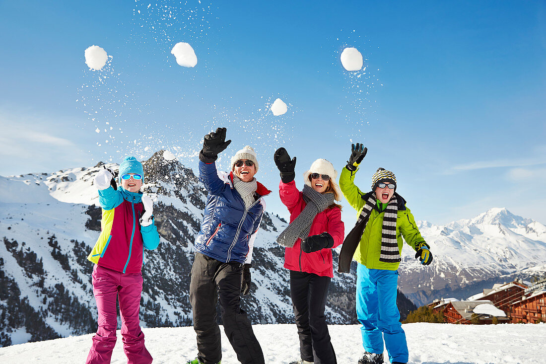 Family throwing snowballs on mountain top