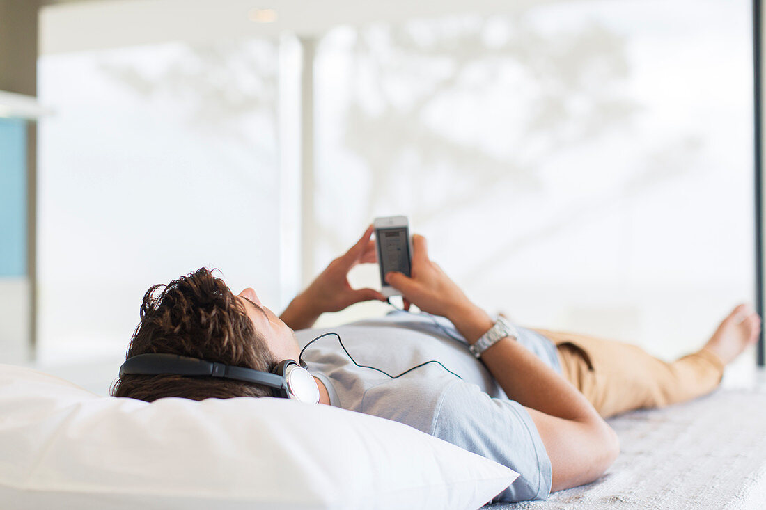 Man listening to music while lying on bed