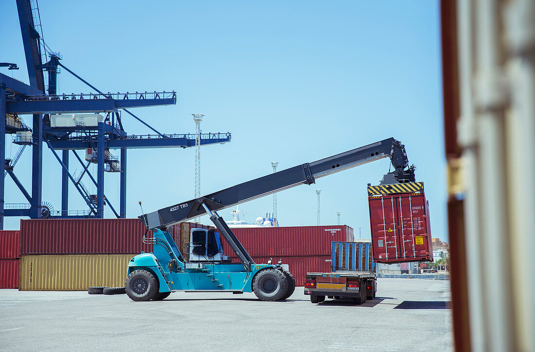 Crane lifting cargo container onto truck