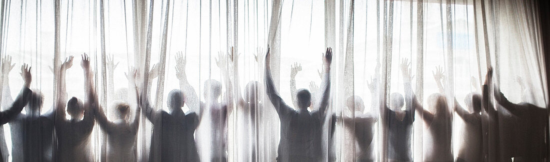 Silhouette of people raising hands