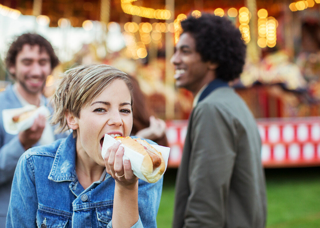 Three young people eating hot-dogs