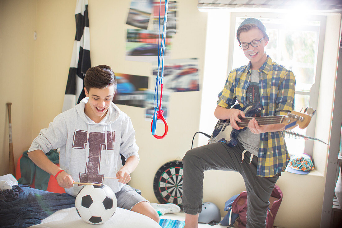 Two teenage boys playing music in room
