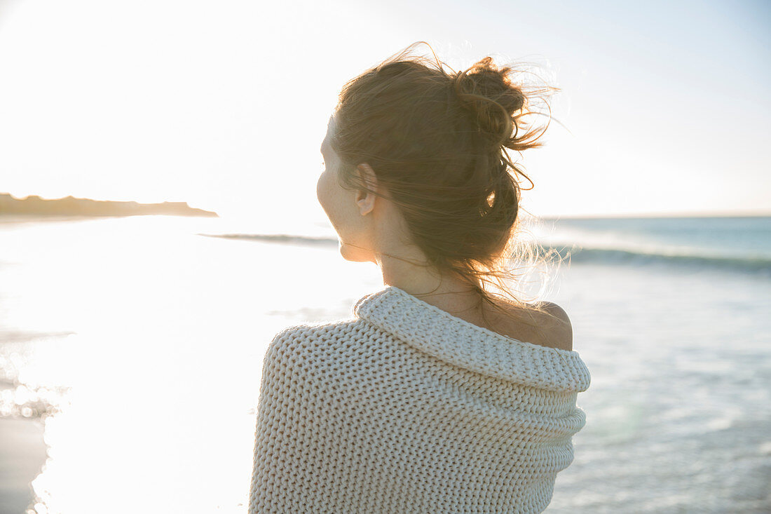 Young woman wrapped in blanket on beach