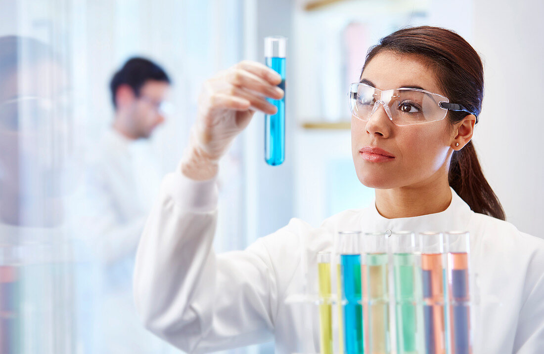 Woman looking at vial with blue fluid