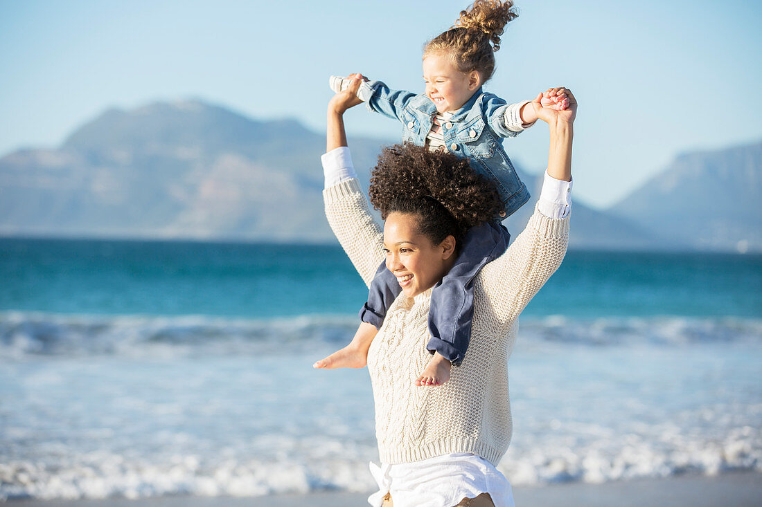 Mother carrying daughter on her shoulders