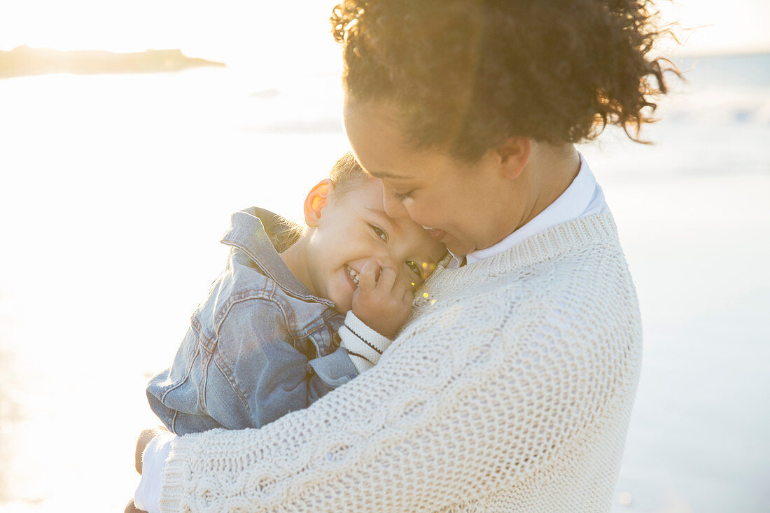 Young woman embracing daughter on beach