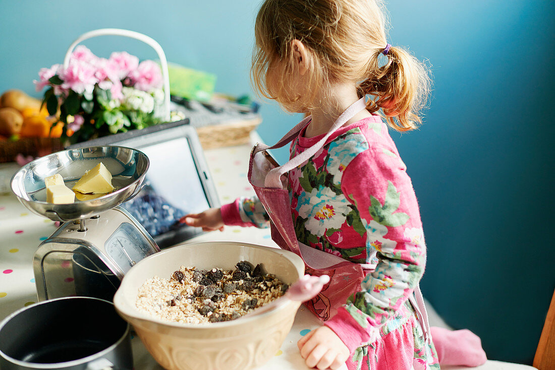 Girl with tablet baking in kitchen