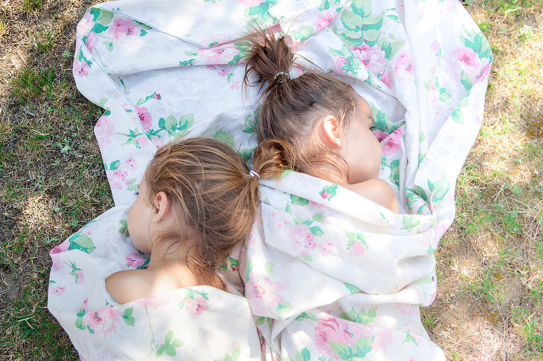 Twin girls napping in floral sheet