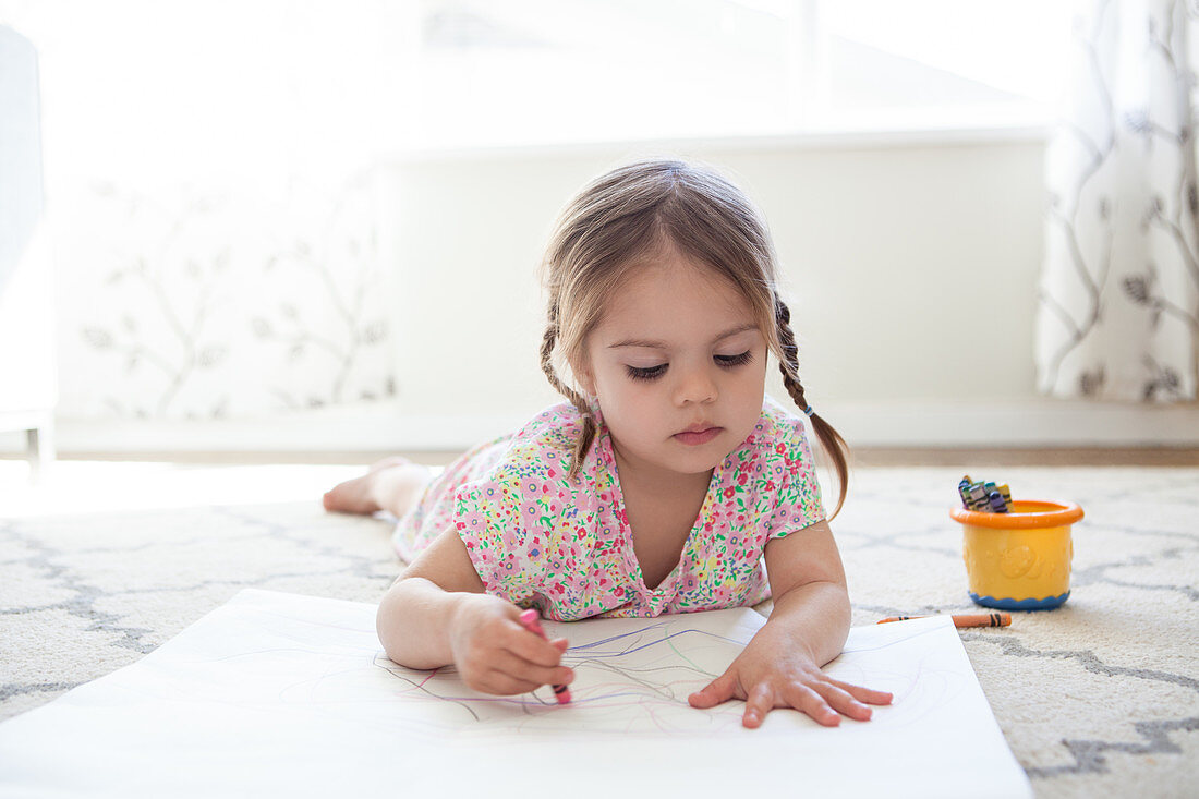 Girl on floor drawing with crayons