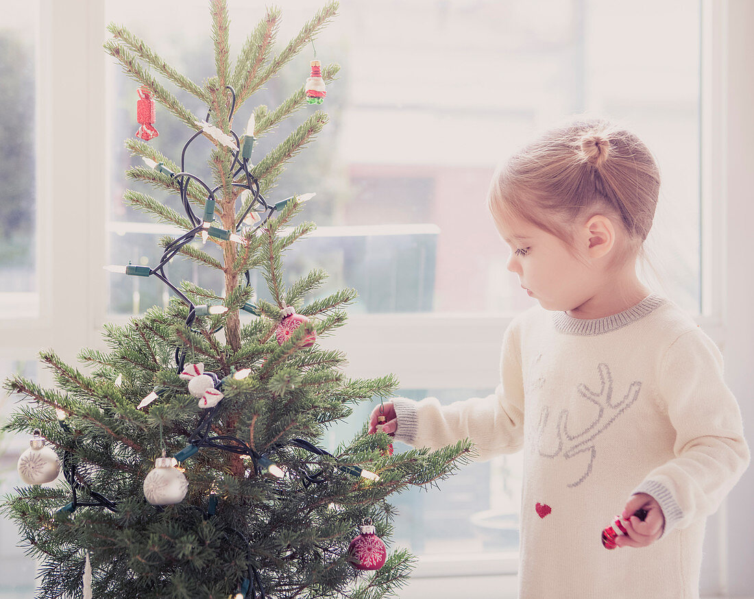 Girl decorating small Christmas tree