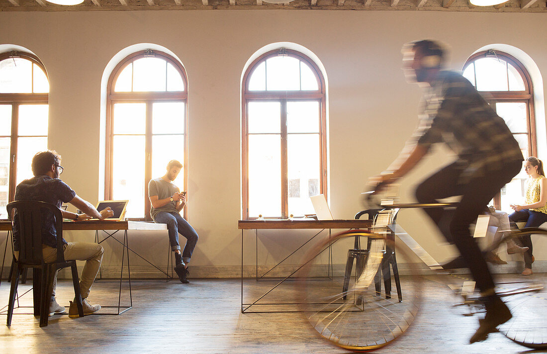 Businessman riding bicycle in open office