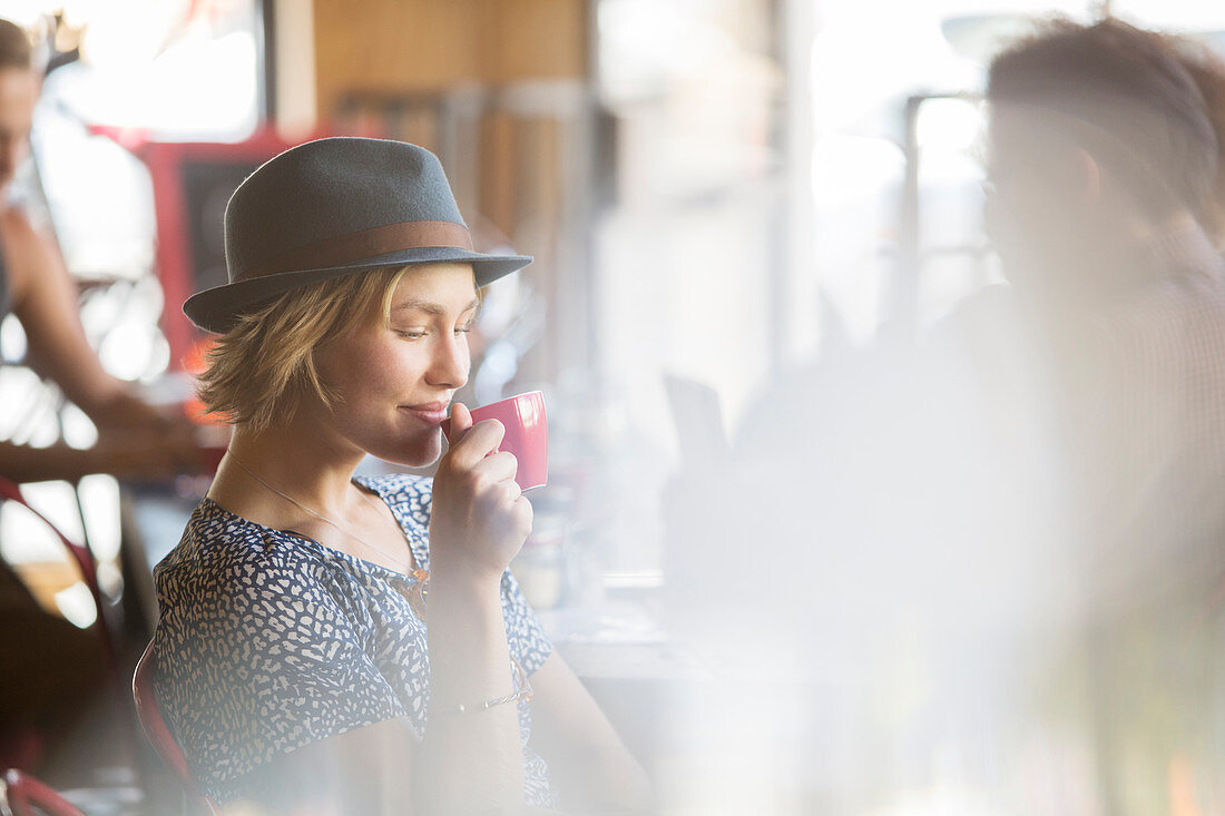 Woman in hat drinking coffee in cafe