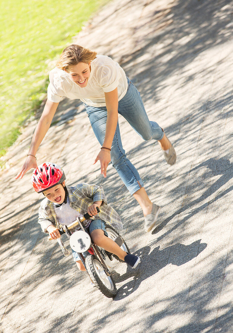 Mother pushing son on bicycle
