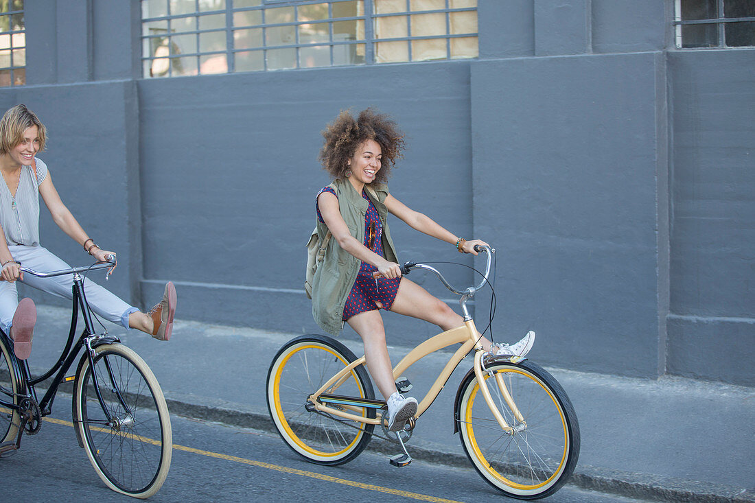 Playful women coasting on bicycles