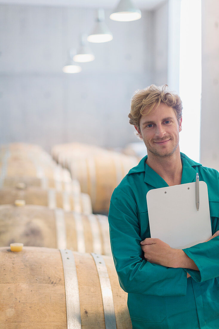 Portrait smiling vintner in winery cellar