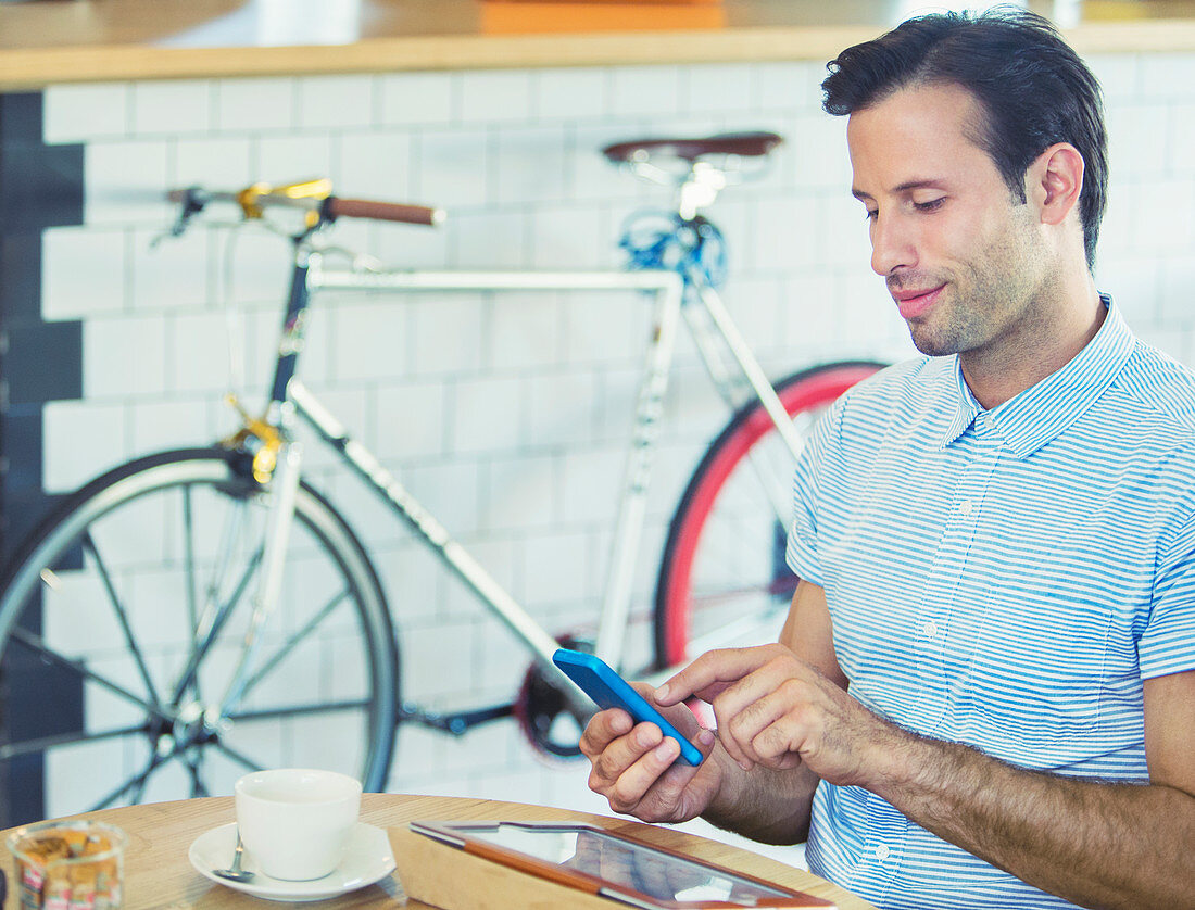 Man texting near bicycle in cafe