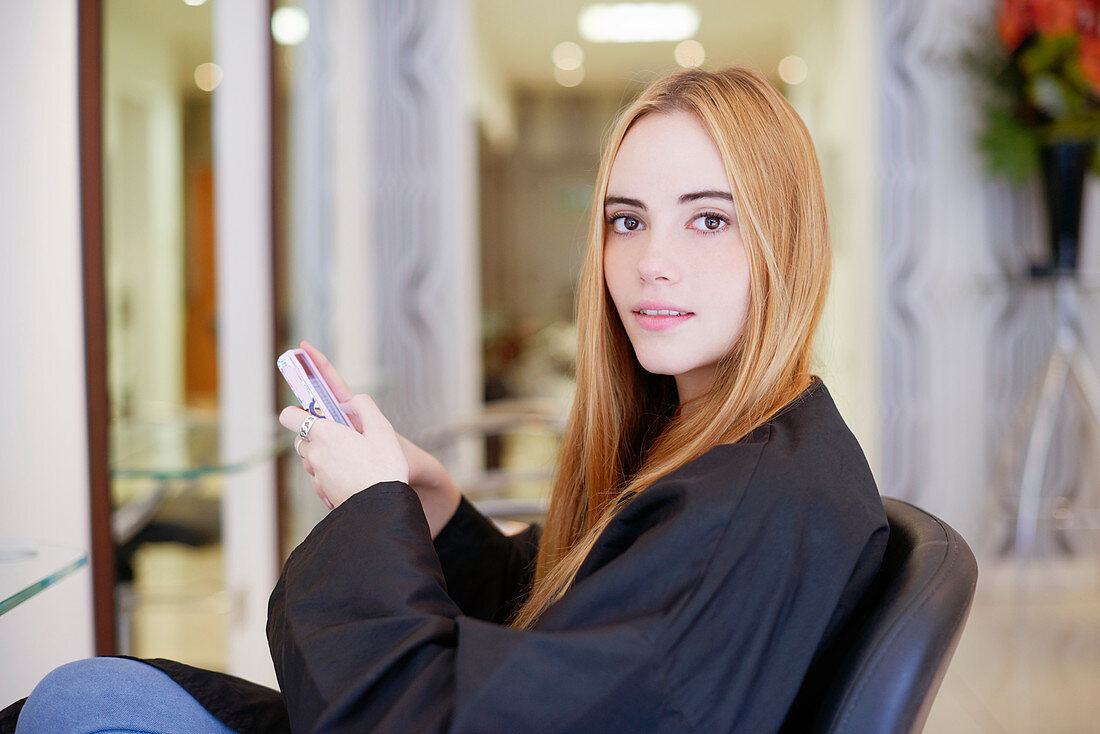 Portrait woman texting in hair salon
