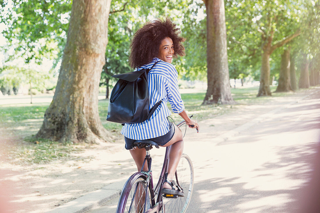 Woman with afro riding bicycle in park