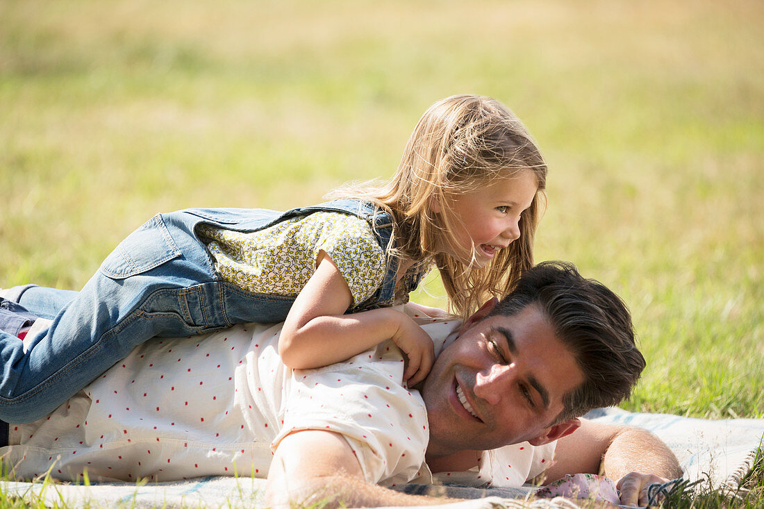 Playful daughter laying on top of father