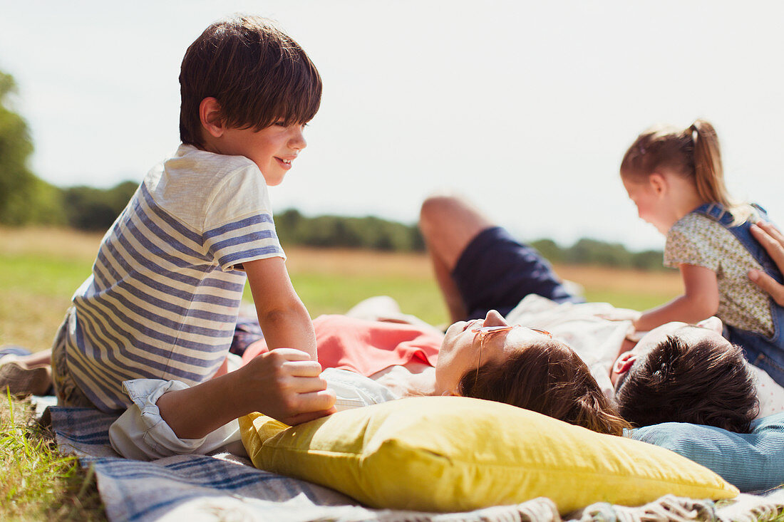 Family relaxing on blanket in sunny field