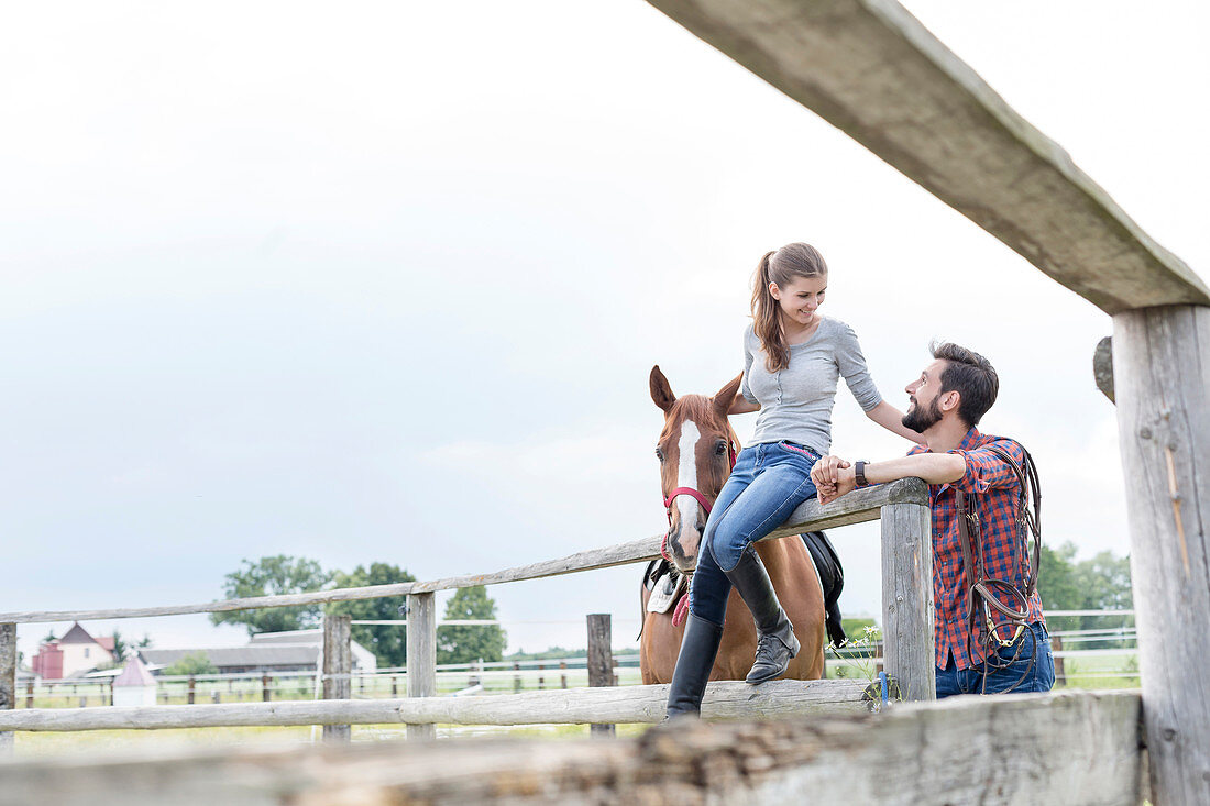 Couple and horse at rural pasture fence