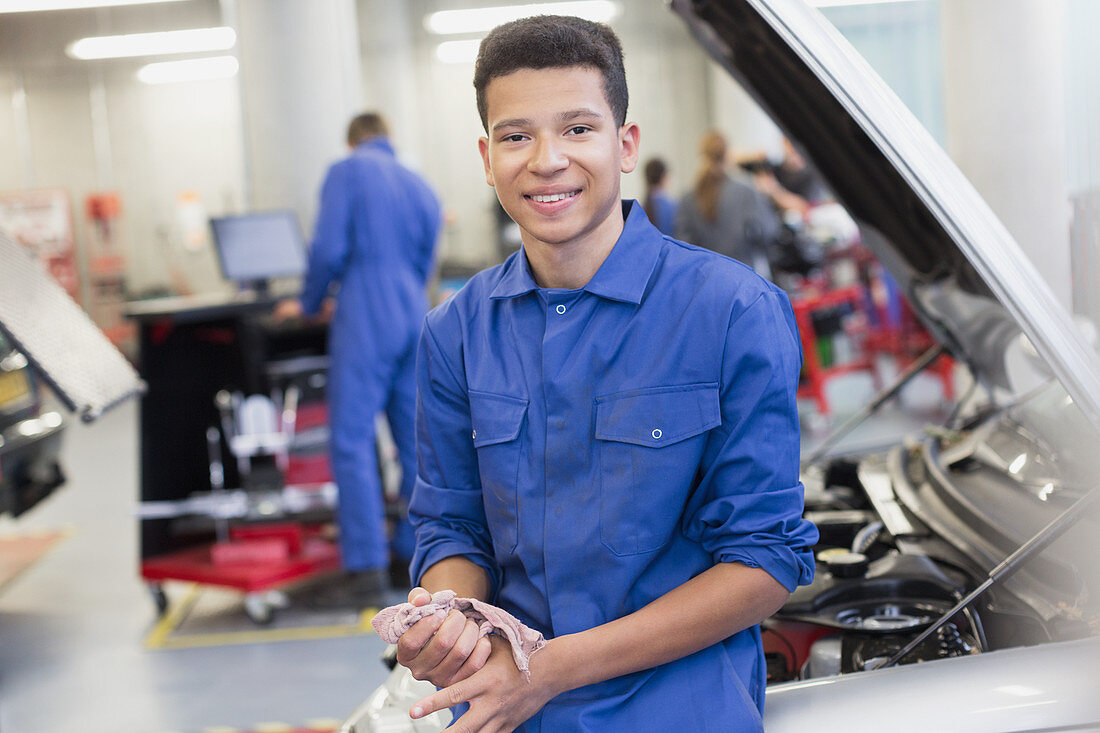 Portrait smiling mechanic leaning on car