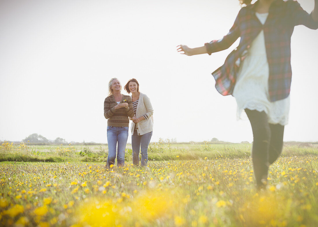 Women watching girl run in meadow