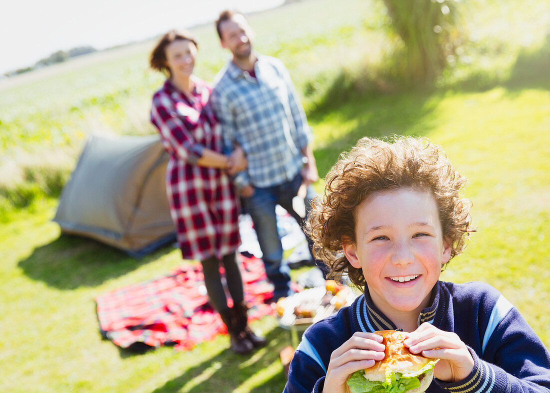 Boy eating hamburger with parents