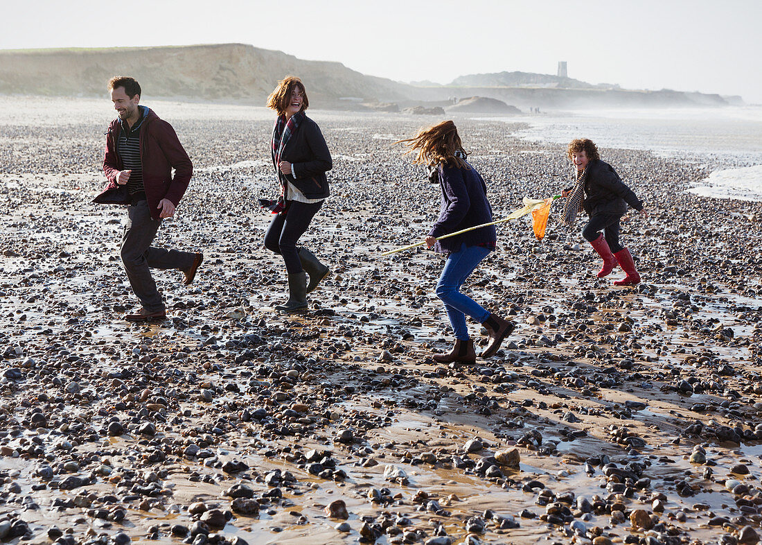 Family running on rocky beach