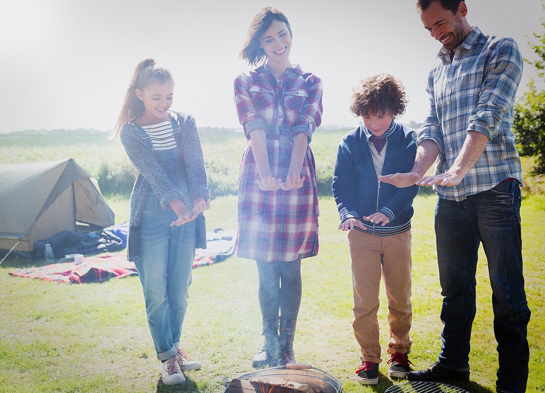 Family warming hands at campfire