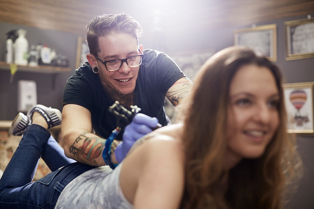 Tattoo artist tattooing woman's back