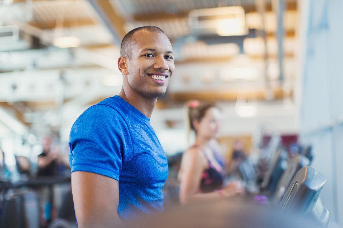 Portrait smiling man on treadmill at gym