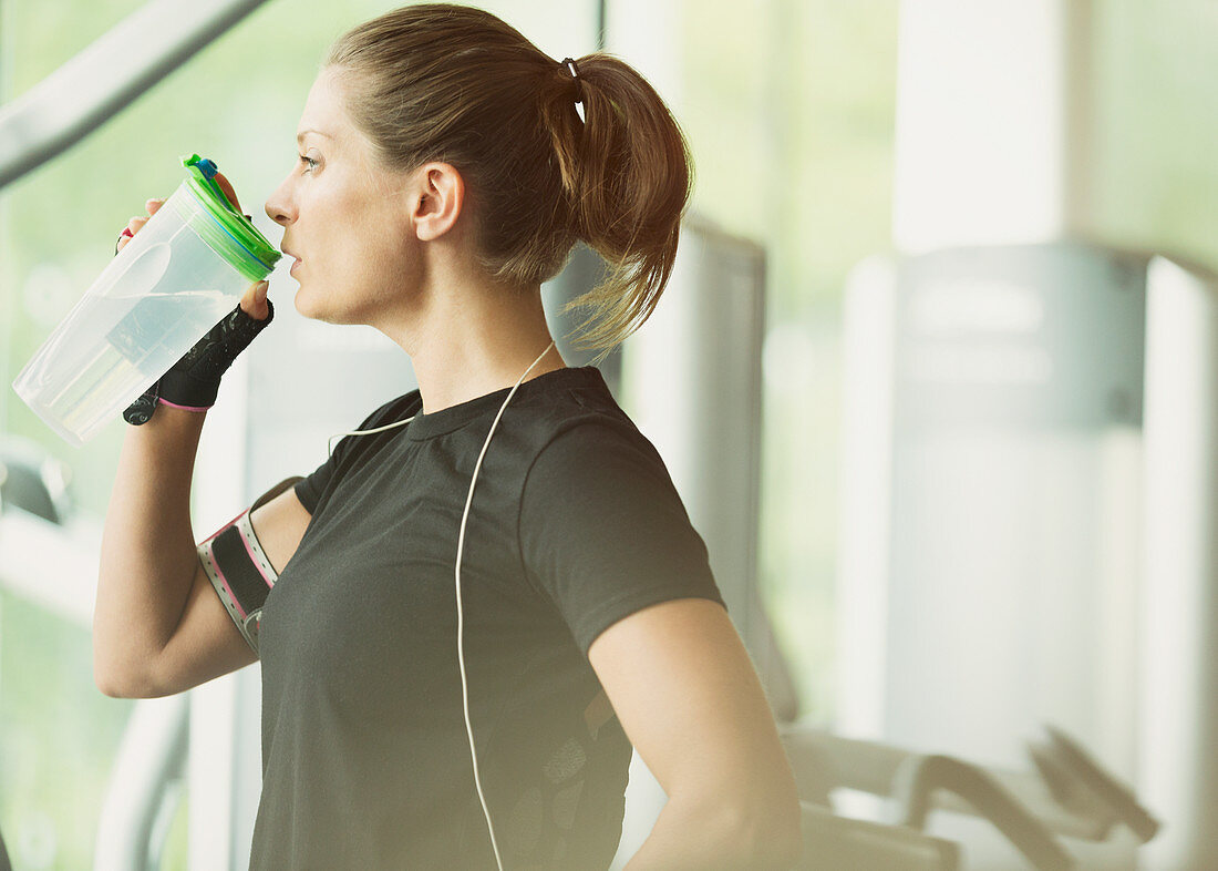 Woman resting and drinking water at gym