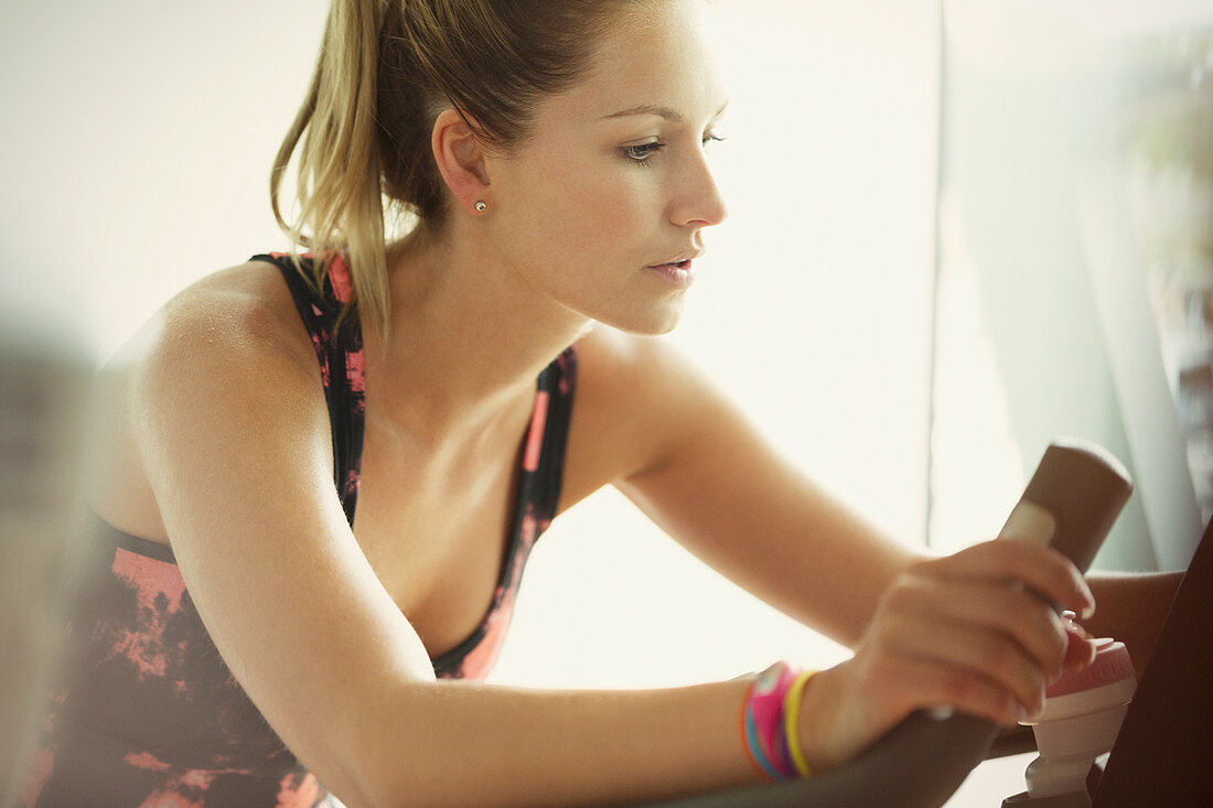 Focused woman using exercise bike at gym