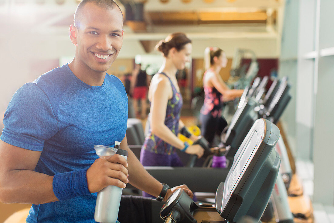 Man with water bottle on treadmill at gym
