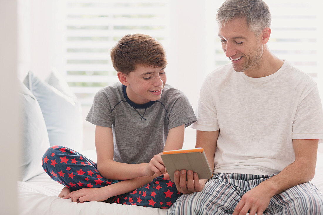 Father and son in pajamas using tablet
