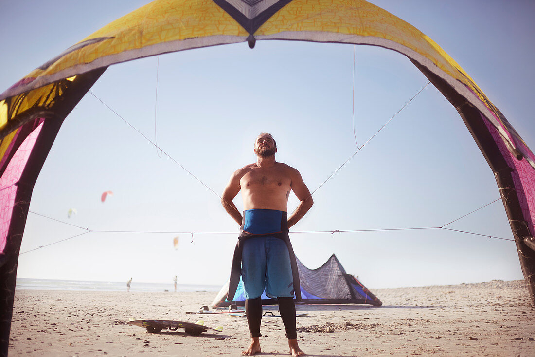 Man preparing to kiteboard on sunny beach
