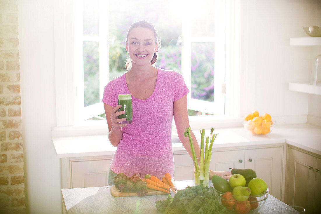 Woman drinking green smoothie in kitchen
