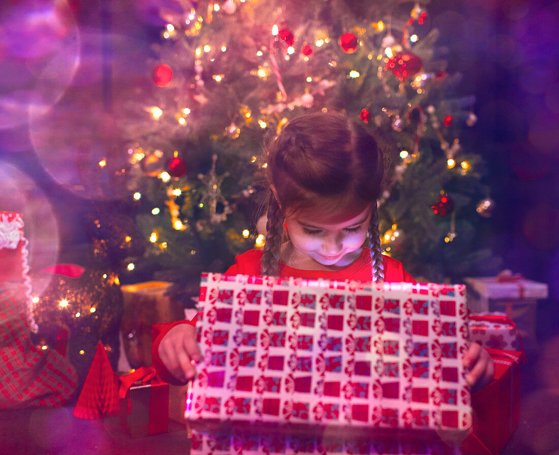 Girl opening illuminated Christmas gift