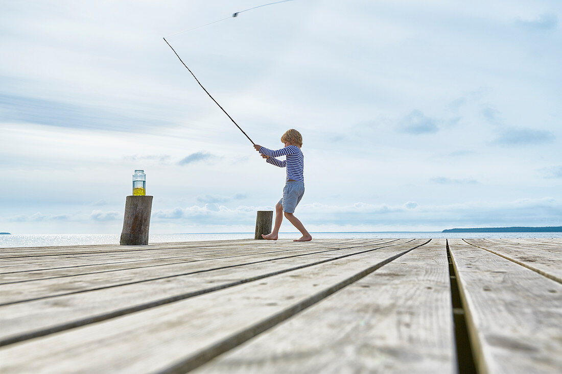 Boy fishing off lakeside dock