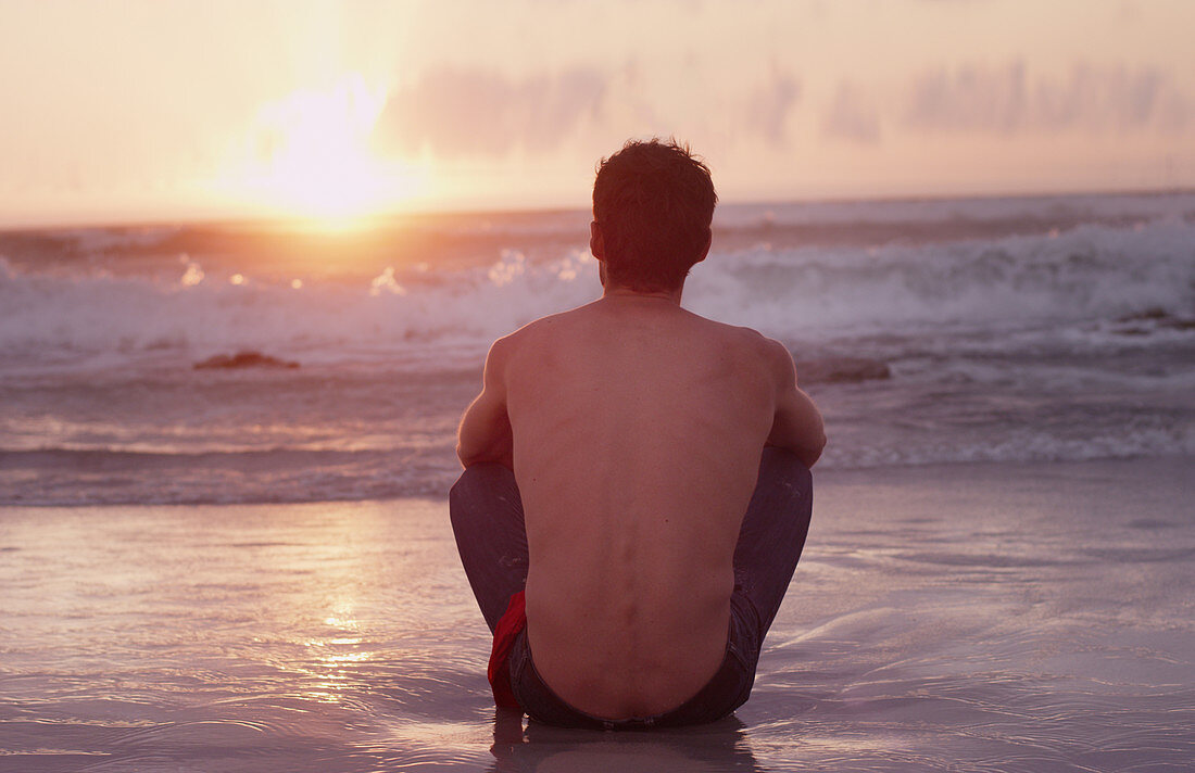 Young man on beach watching sunset